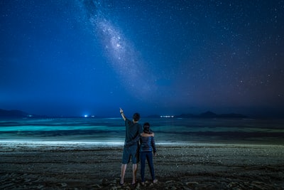 穿着黑色夹克的男人在夜间站在海滩上